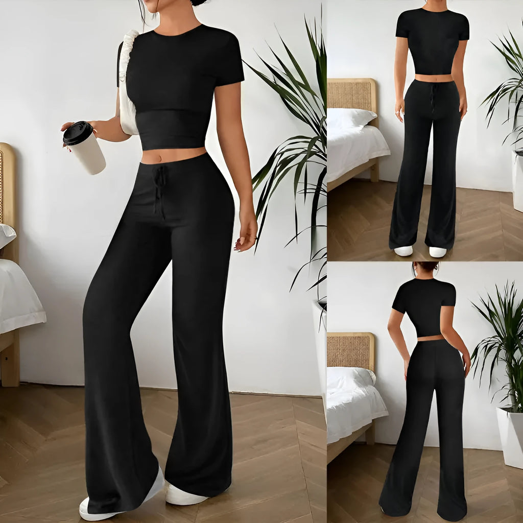 Women's black high waist trousers and short sleeve t-shirt co-ord set laid flat.