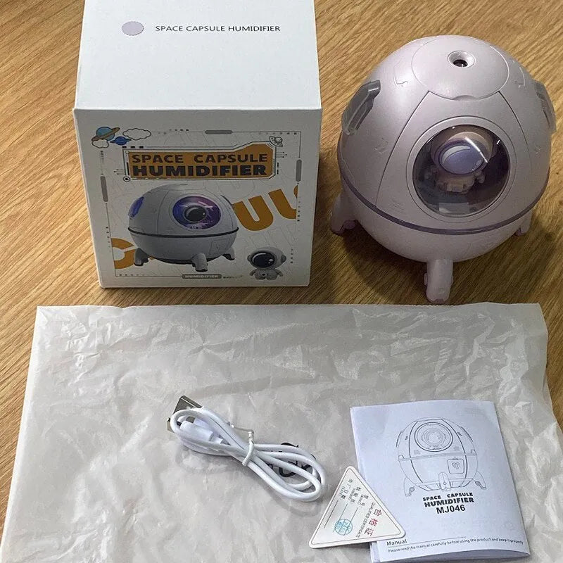 Purple astronaut-shaped USB desktop humidifier with colourful LED light on wooden desk