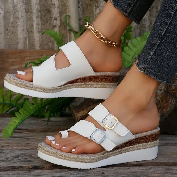 White women's wedge sandals with a woven patent leather upper, peep toe, and a finger-fit ankle strap on a rubber sole.