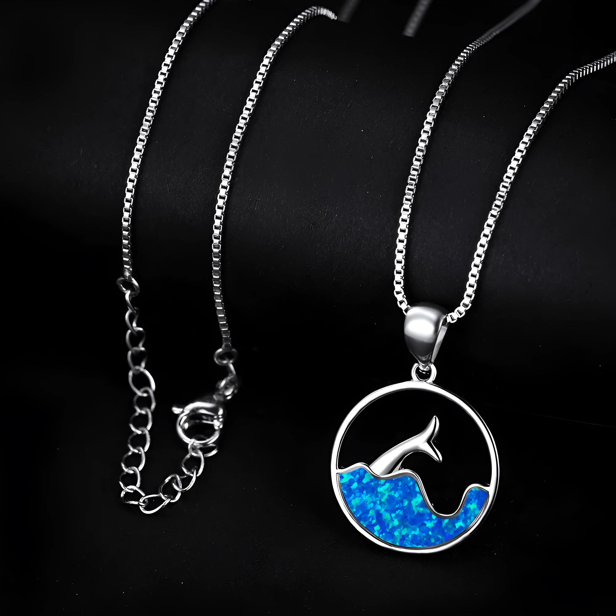 Gold tone geometric fishtail pendant necklace with a round blue opal centre on a chain.
