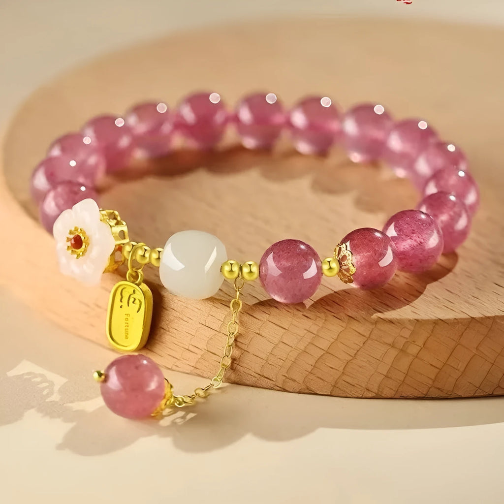 Handmade strawberry quartz crystal bracelet with peach blossom design on a wrist.