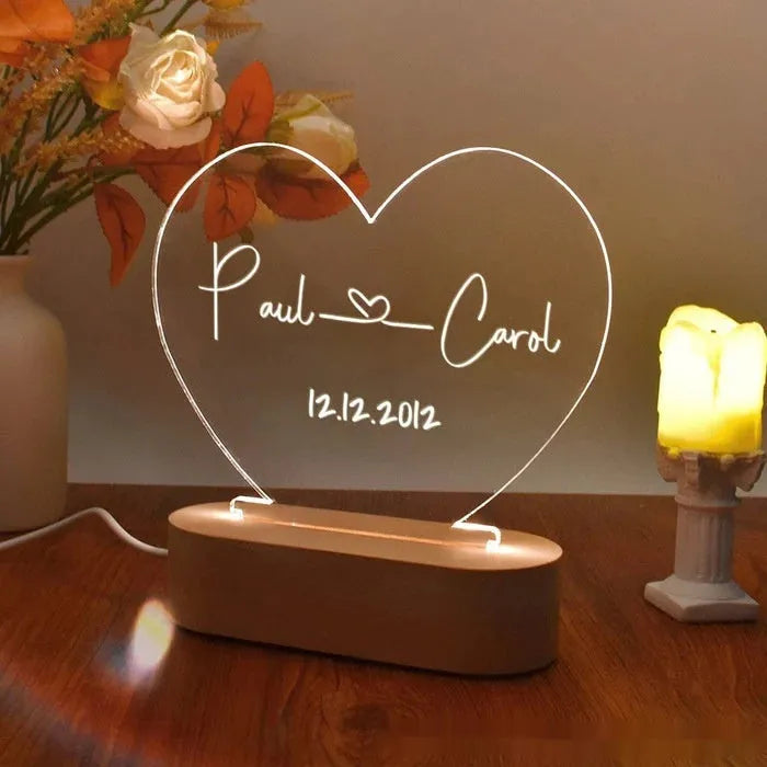 Custom acrylic night light with engraved names illuminated by LED base on bedside table