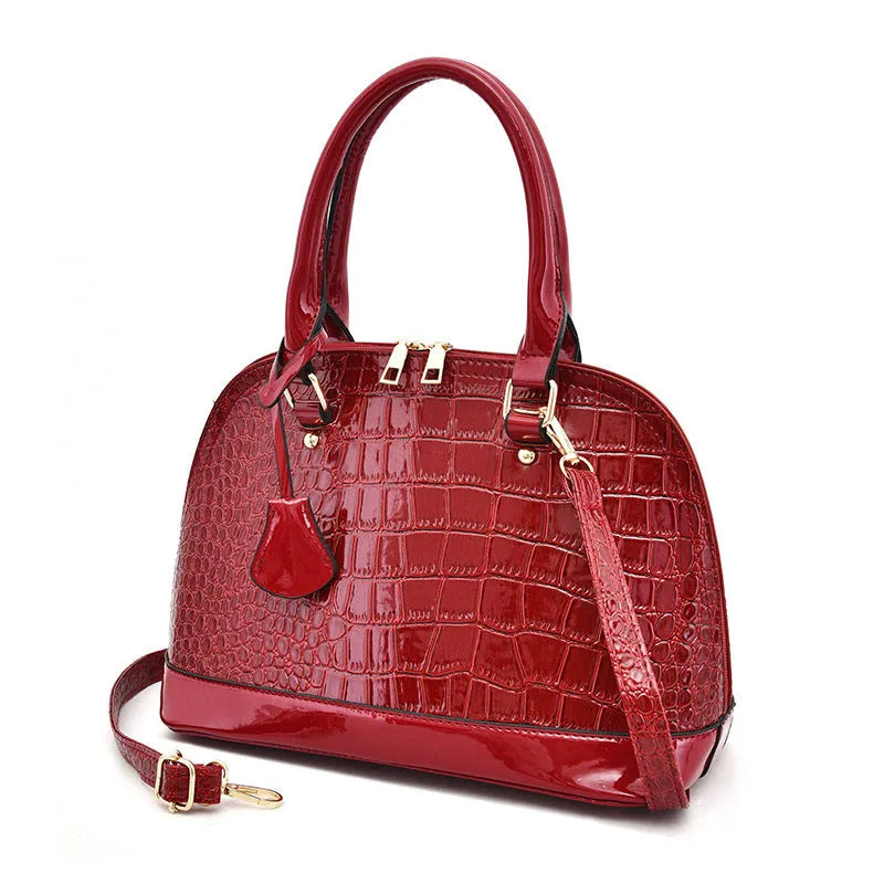 Large shiny black PU leather crossbody bag with shell shape, showing interior polyester lining and shoulder strap