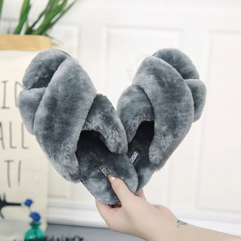 Women's black cross open-toe fur slippers with a patterned non-slip sole on a wooden floor.