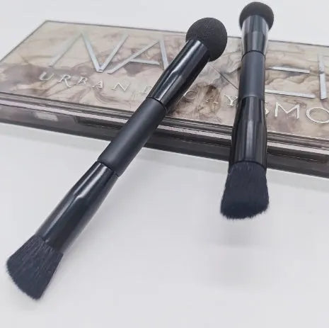 Double-headed concealer brush with tapered bristles and a miter sponge on a long black wooden handle.