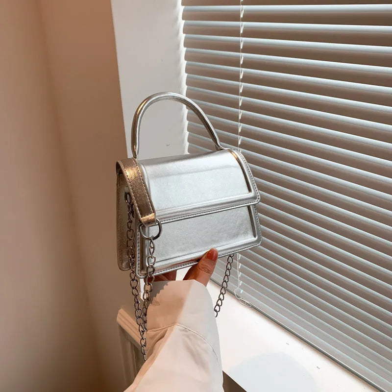 Retro shoulder bag with horizontal square shape in silver colour showing sewing line details