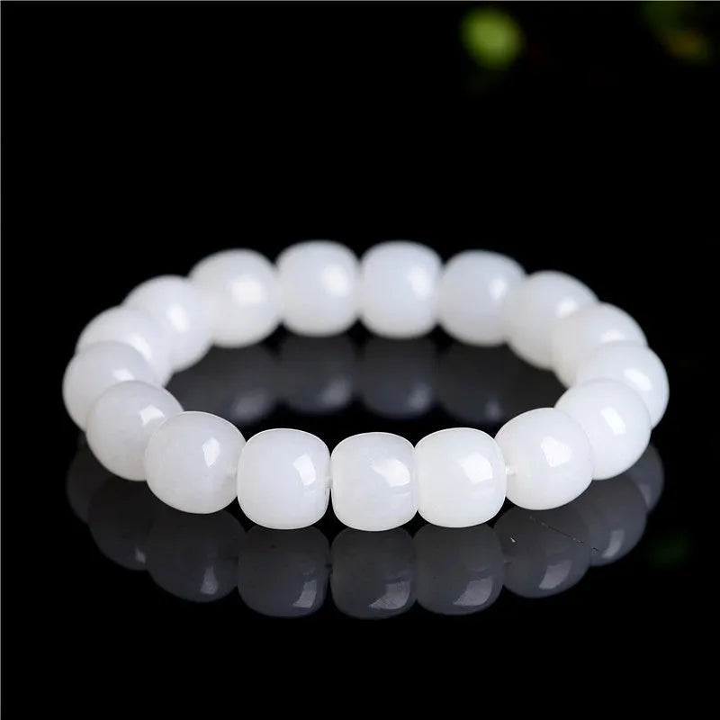 White Hetian jade barrel bead bracelet on a wrist, showing smooth oval beads on a string.