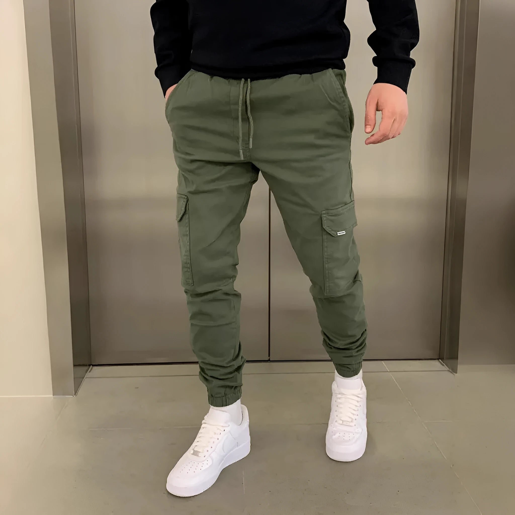 Man wearing light blue loose-fit casual trousers with patch pockets on the legs.