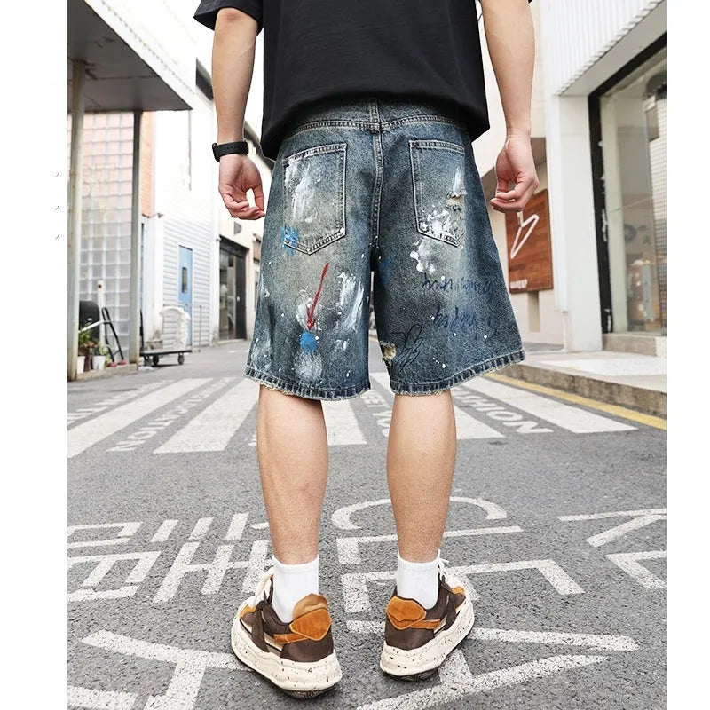 Blue men's denim jeans shorts with graffiti print and ripped details, showing straight leg and zipper fly.