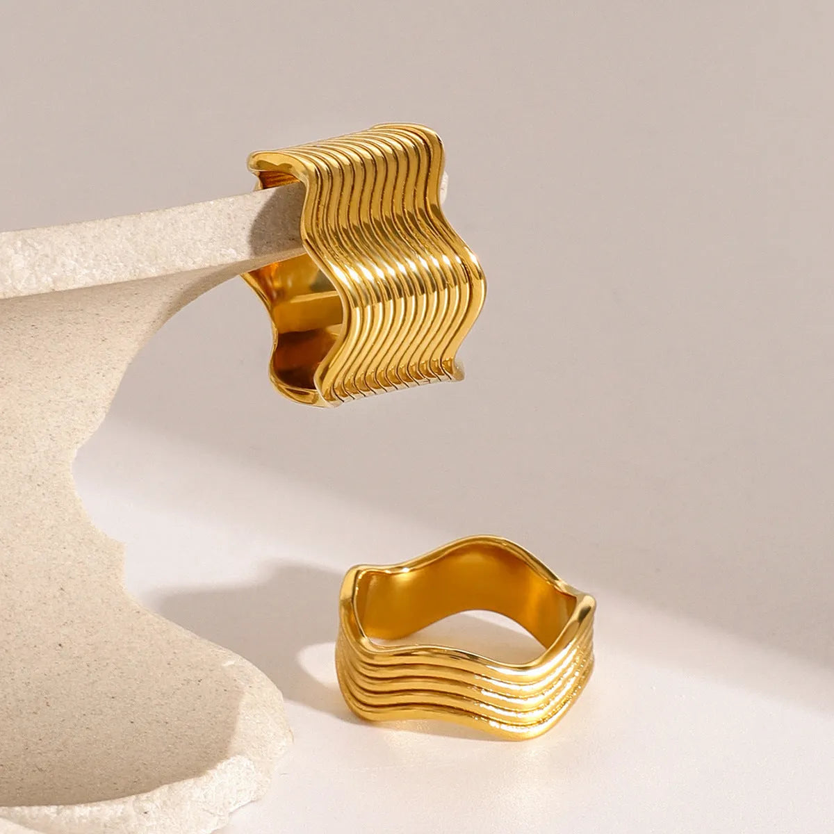 Silver stainless steel wide band ring with a geometric wave pattern surface design.