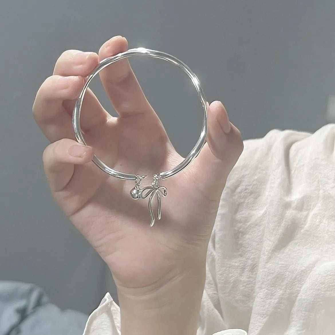 Silver bow adjustable bracelet with bell opening clasp on wrist