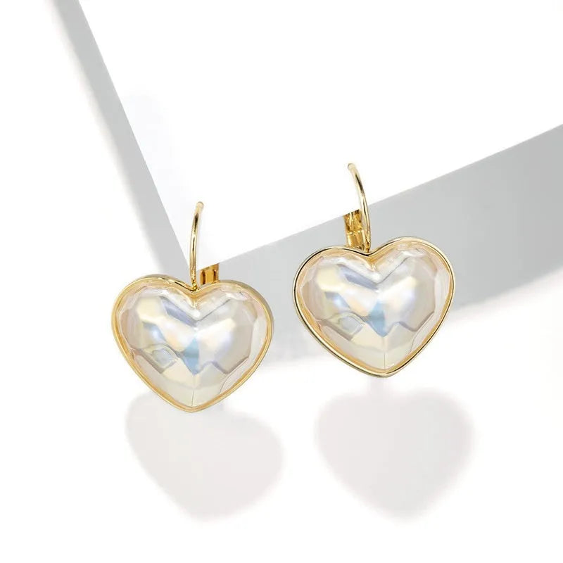 A pair of gold-coloured minimalist alloy ear clip earrings for women on a plain background.