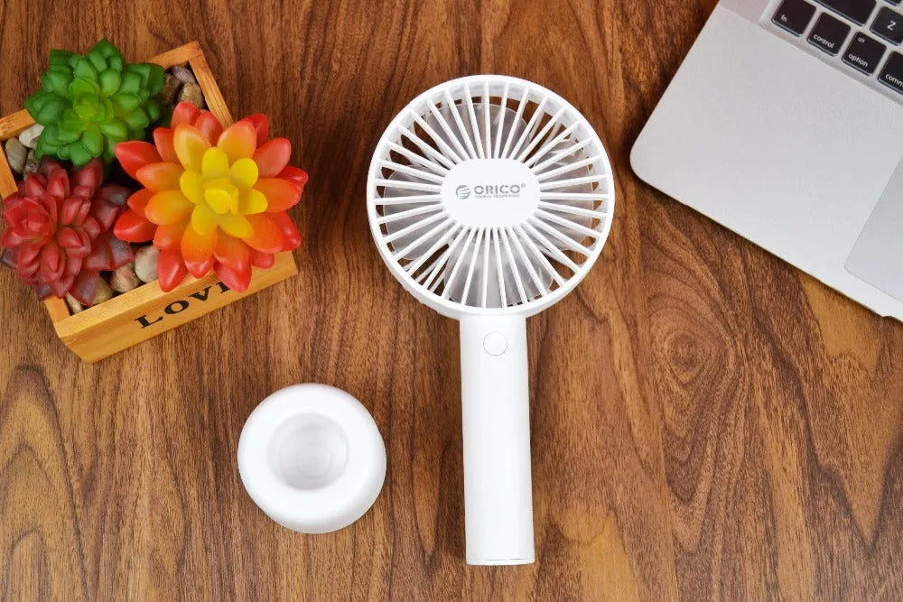 White ORICO FH1 portable USB desktop fan with rechargeable battery on a table.