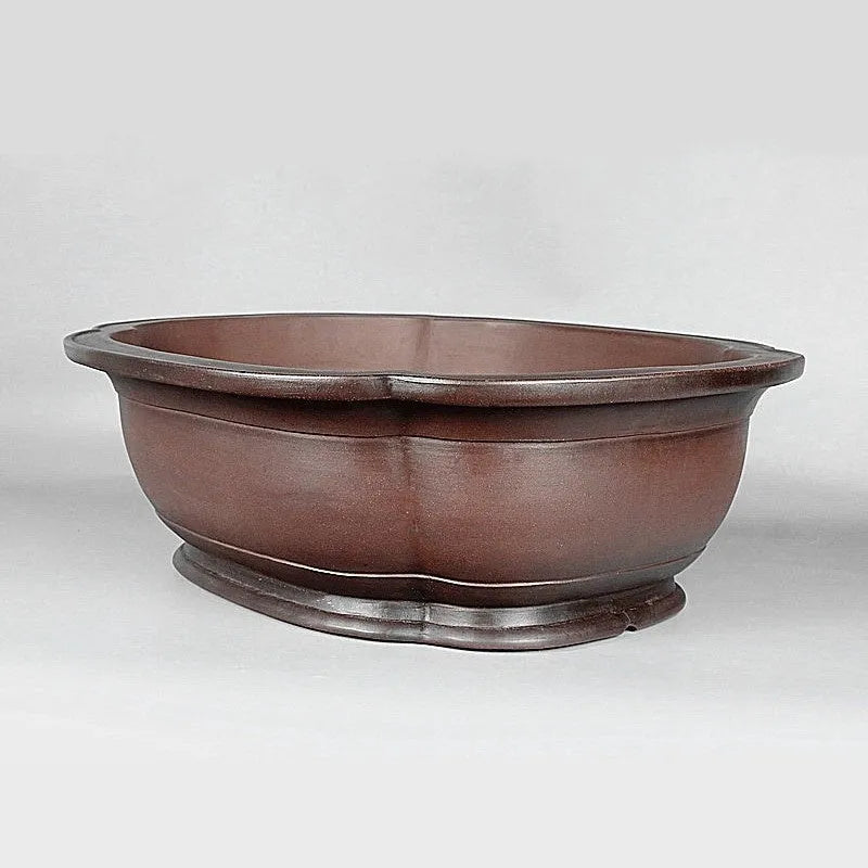 Handmade antique crabapple shaped purple clay flower pot on a wooden floor.