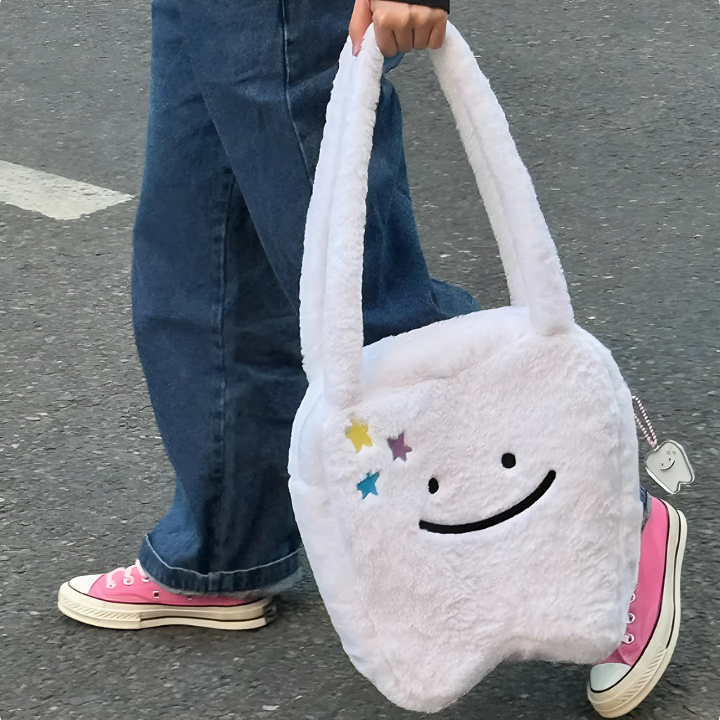 White plush large tooth design shoulder tote bag with zipper closure shown from the front.