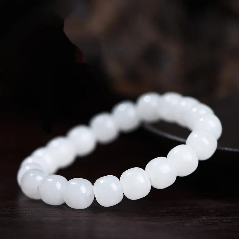 White Hetian jade barrel bead bracelet on a wrist, showing smooth oval beads on a string.