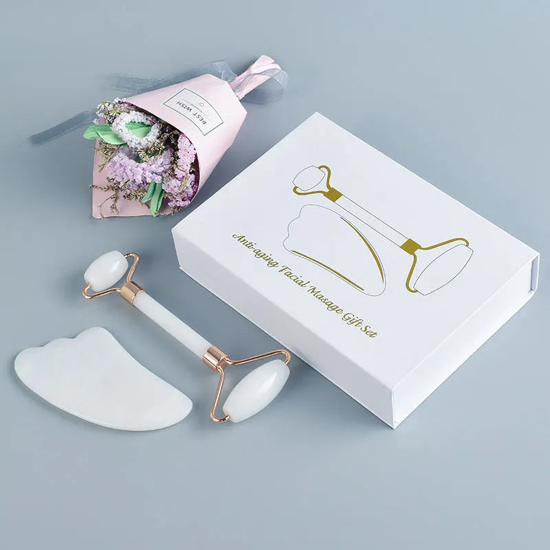 White jade facial roller set with double-headed roller, claw tool, and gua sha board on a wooden table.