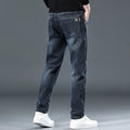 Men's slim straight casual trousers in blue-grey, showing a loose fit and zip fly detail.