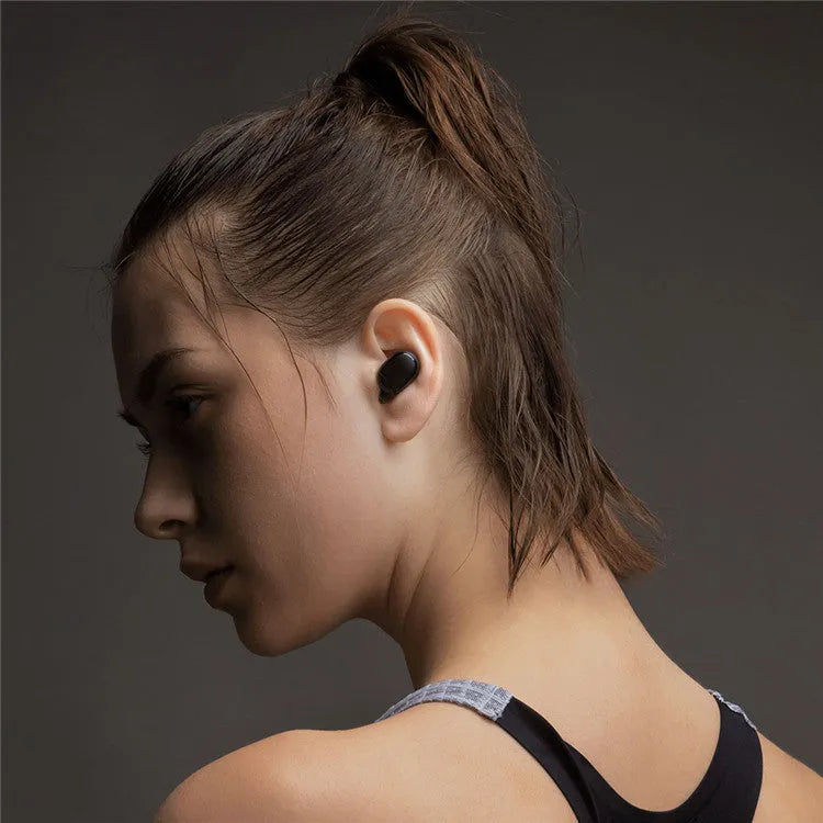 Redmi AirDots black true wireless earbuds next to their compact white charging case.
