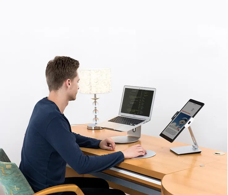 Black folding aluminium desktop stand holding a tablet at an angle, showing 360° rotation and silicone grips.