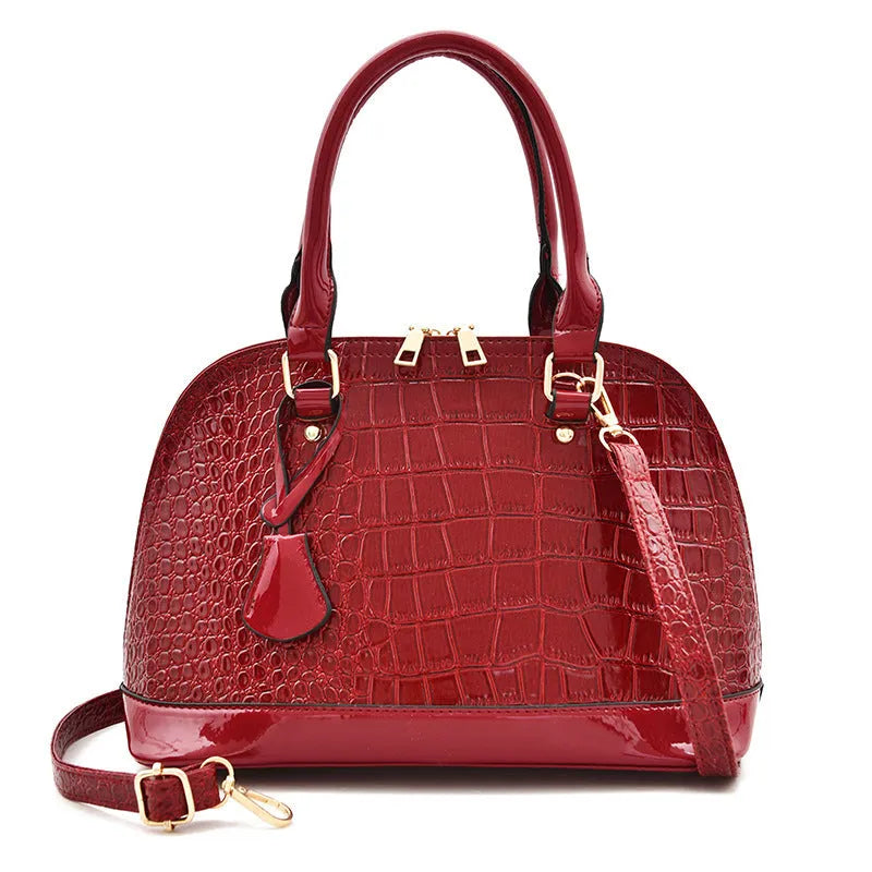 Large shiny black PU leather crossbody bag with shell shape, showing interior polyester lining and shoulder strap