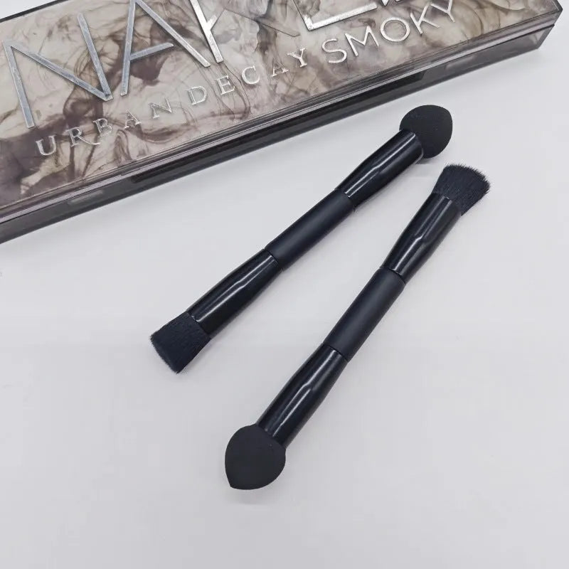 Double-headed concealer brush with tapered bristles and a miter sponge on a long black wooden handle.