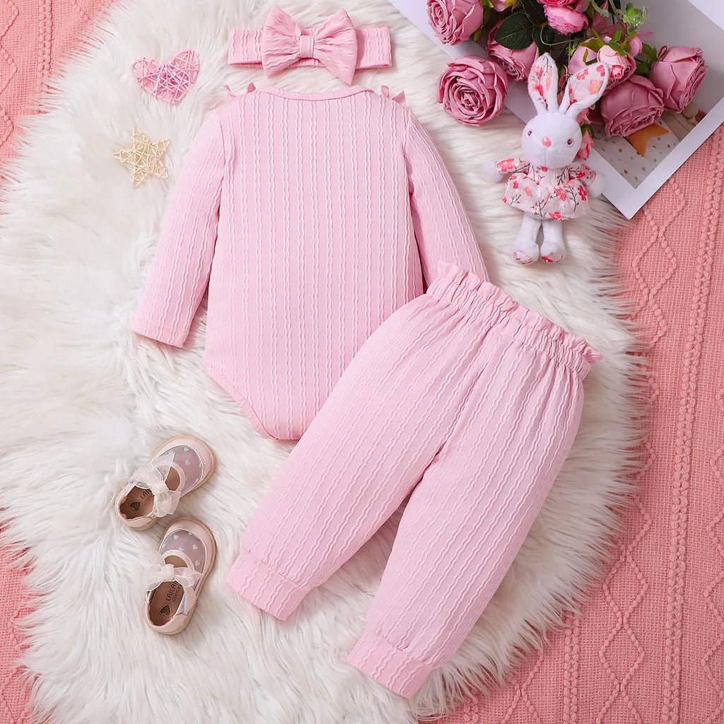 Pink baby girl three-piece set with ribbed frill long sleeve romper, pants, and matching headscarf on white background