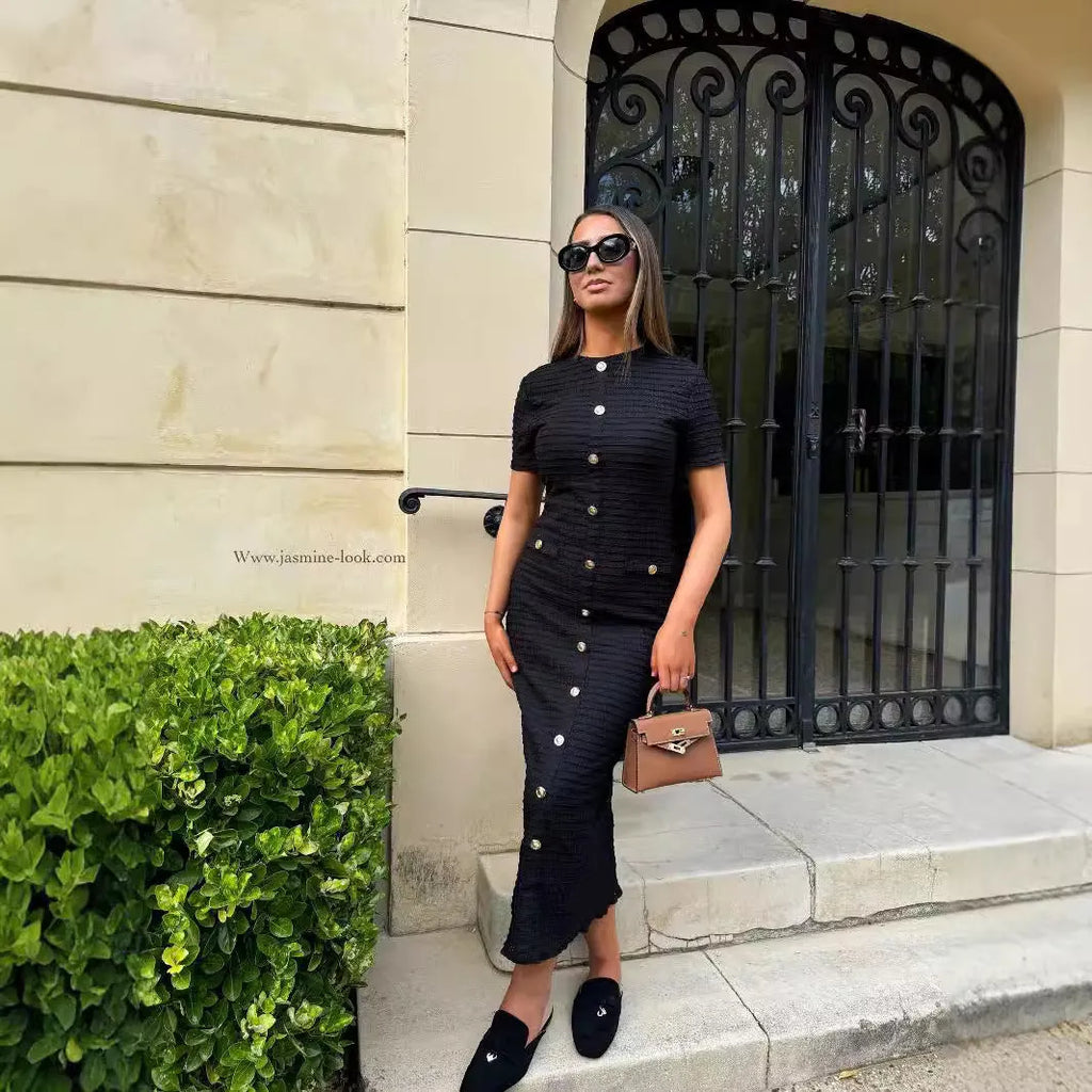 A woman wearing a black French retro slim fit knitted long sleeve dress with button detail.
