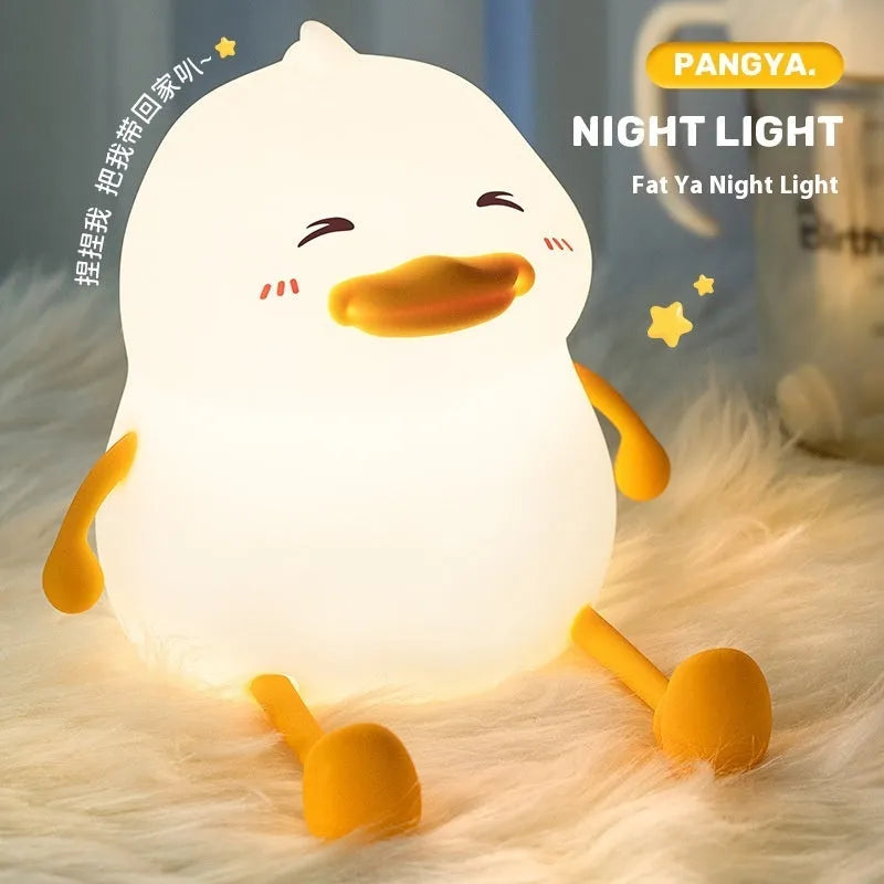 Chubby white silicone rechargeable night light on a wooden desk, showing phone holder function.
