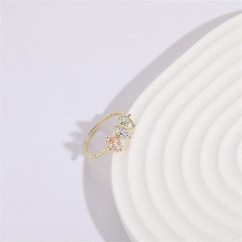 Women's gold-coloured ring with a horse eye design and three coloured zircon stones on a geometric band.