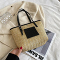 Straw woven women's shoulder bag in black with sewing thread detailing and three-dimensional pockets