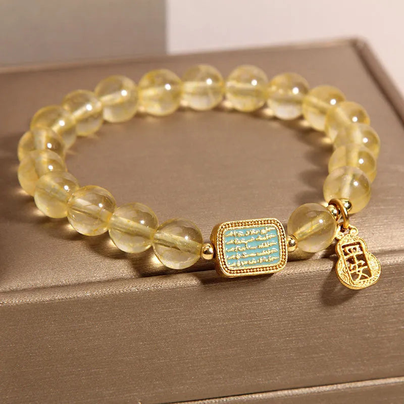 Women's yellow citrine crystal bracelet with sparkling rhinestone details on a white background.