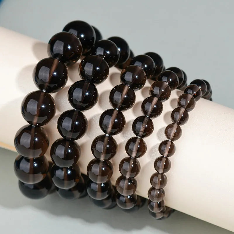 Hand-woven black obsidian bracelet with round beads, shown as a couple's set on a wrist.