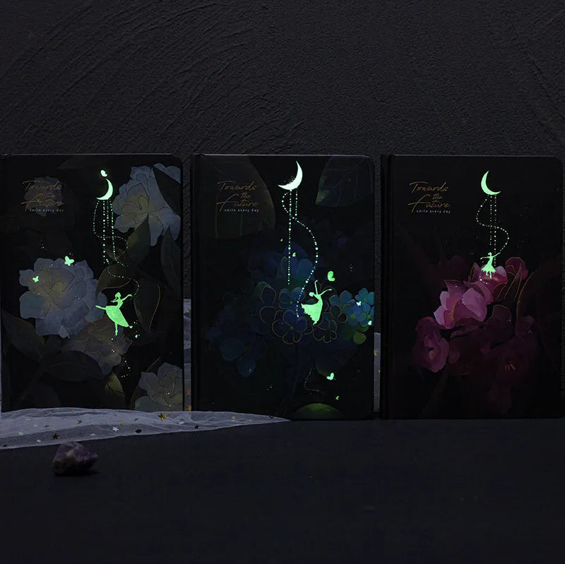 A5 notebook with luminous cover open to show internal colour illustrations, in Deep Blue, Gold, Light Blue, and Purple options