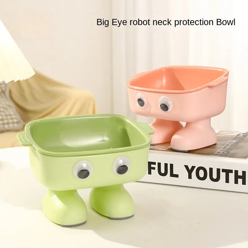 Green cartoon robot-shaped elevated cat bowl with tilted design and non-slip base on a table.