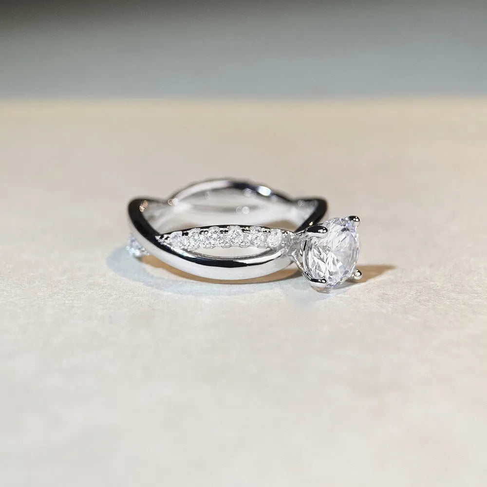 A geometric twisted silver ring with a 1 karat moissanite stone in a four-claw setting.