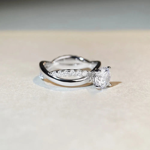 A geometric twisted silver ring with a 1 karat moissanite stone in a four-claw setting.