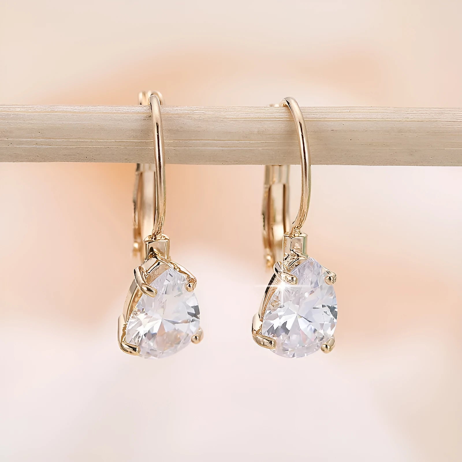 Drop-shaped women's fashion earrings in gold or platinum finish with an inlaid gem