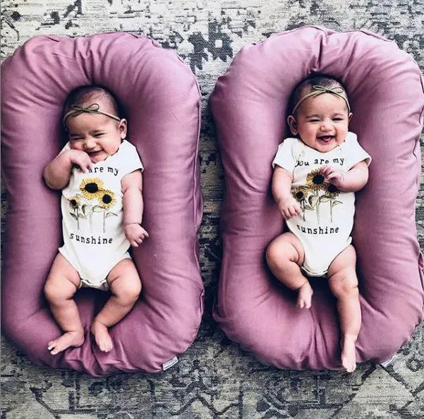 Beige portable cotton baby nest crib for newborns on a neutral background