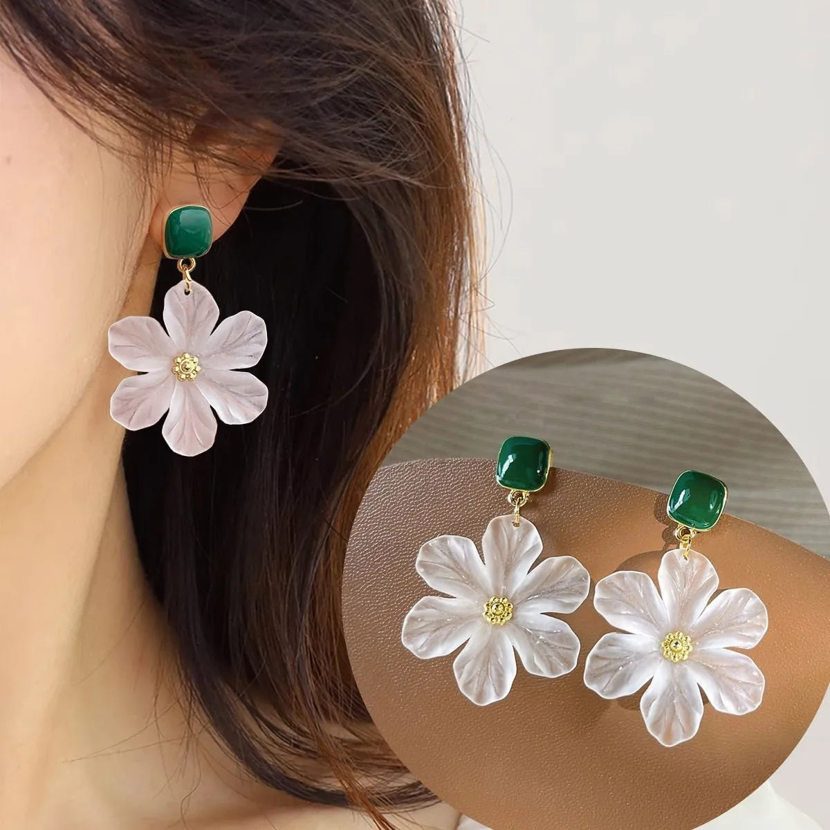 A pair of dark green alloy drop earrings with a floral design and clip-on fittings.