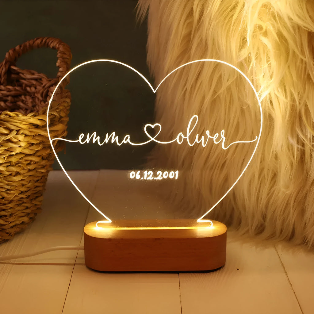 Custom acrylic night light with engraved names illuminated by LED base on bedside table