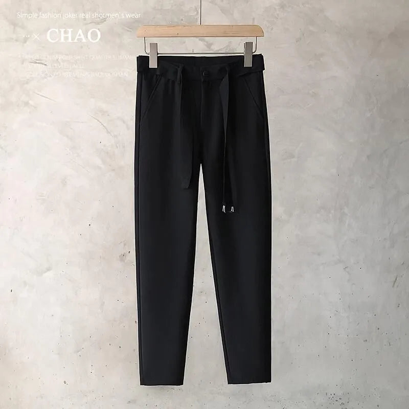 Boy wearing slim straight tapered wool trousers in a grey colour, showing the straight leg opening and belt loops.
