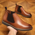 A pair of black formal pointed-toe leather boots with a square heel and rubber sole.