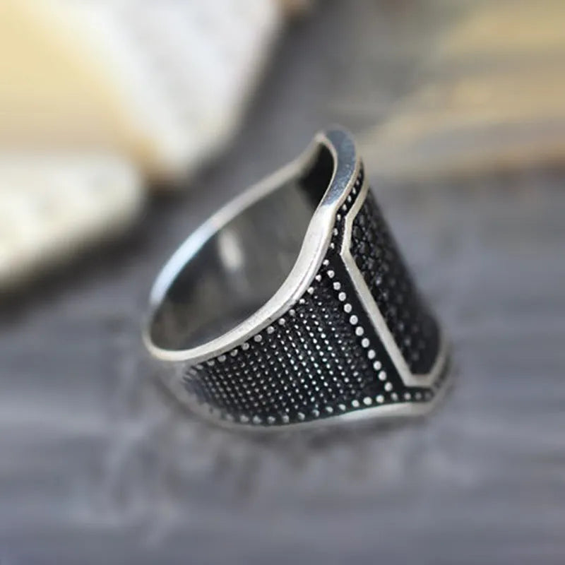 Black alloy ring with copper inlay detailing and a central zircon stone.