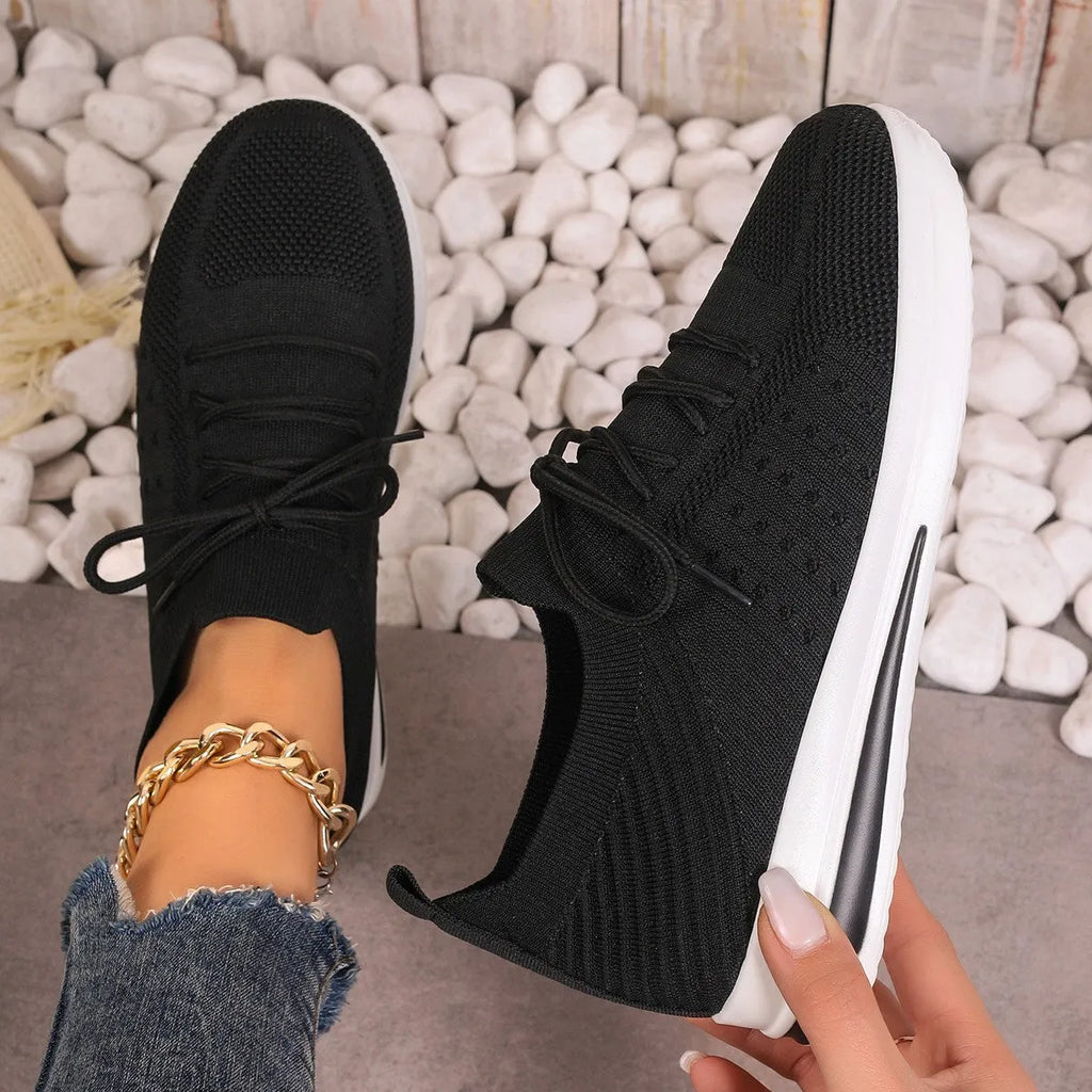 Women's low-top sneakers in black with fly-knit PU upper and front lace-up design.