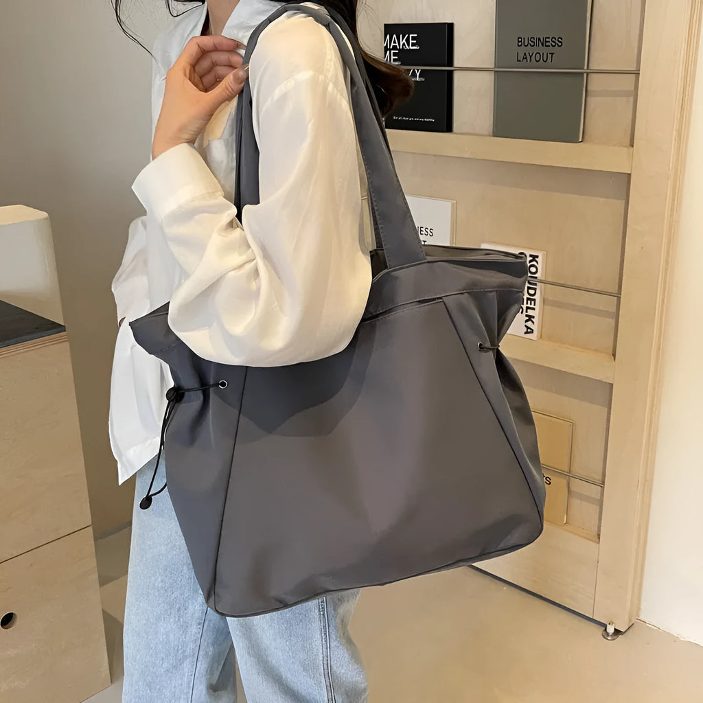 A soft folding Oxford cloth tote bag in a choice of five colours: black, light grey, dark grey, brown, and purple.