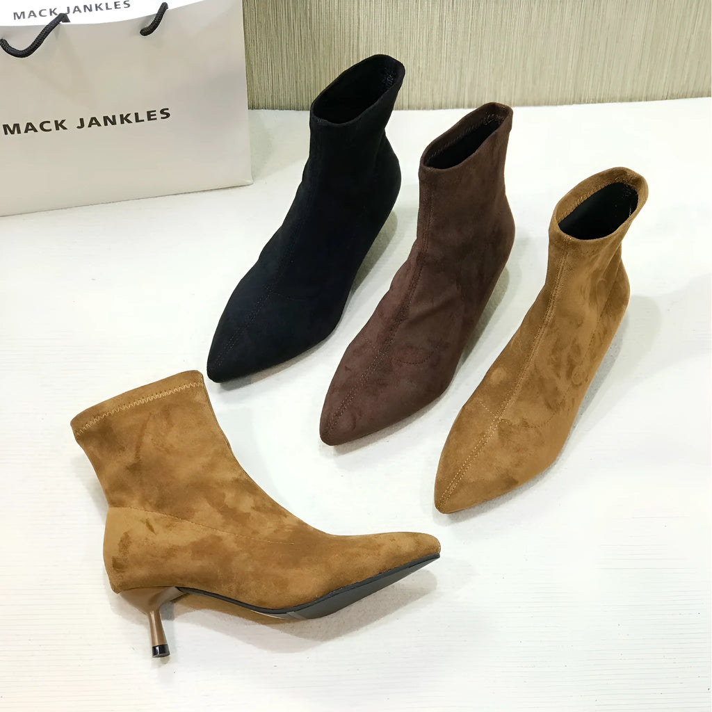 Black women's pointed toe Martin ankle boots with a high stiletto heel on a model.