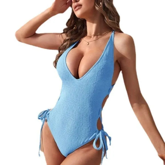 Women's solid colour hollow backless one-piece swimsuit with tether detail on a neutral background.