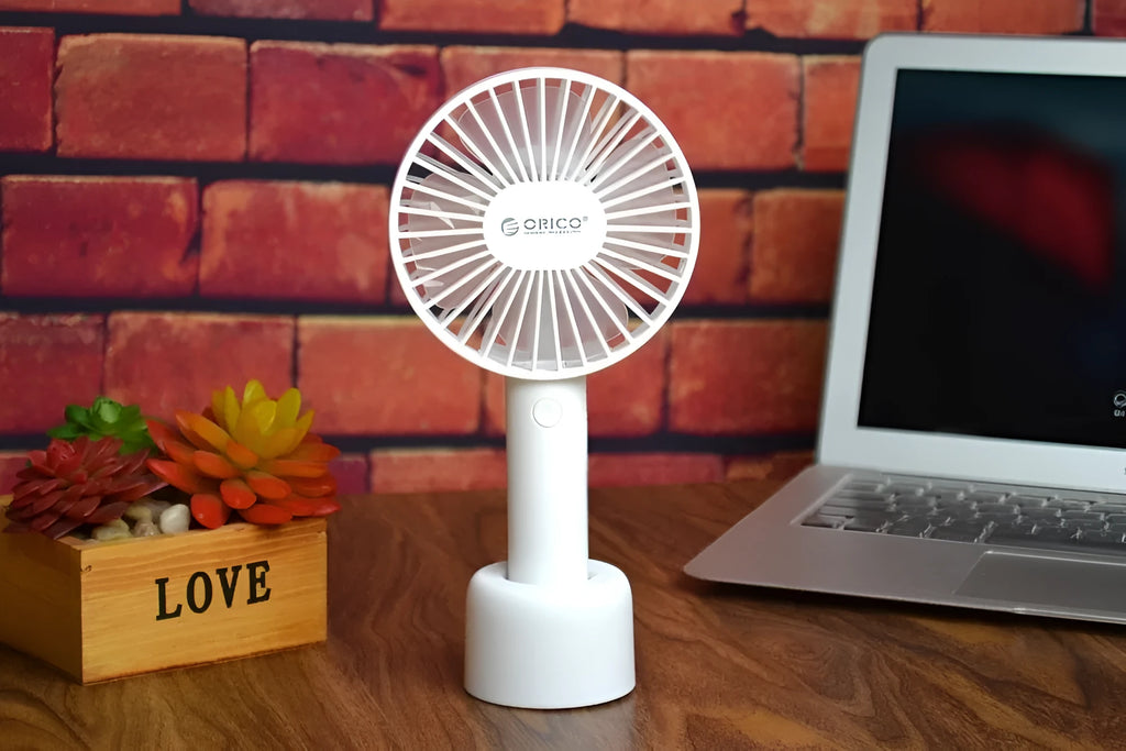 White ORICO FH1 portable USB desktop fan with rechargeable battery on a table.