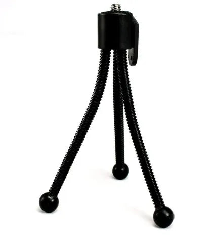 Small silver mini tripod with ball head shown extended on a desktop next to a mobile phone.